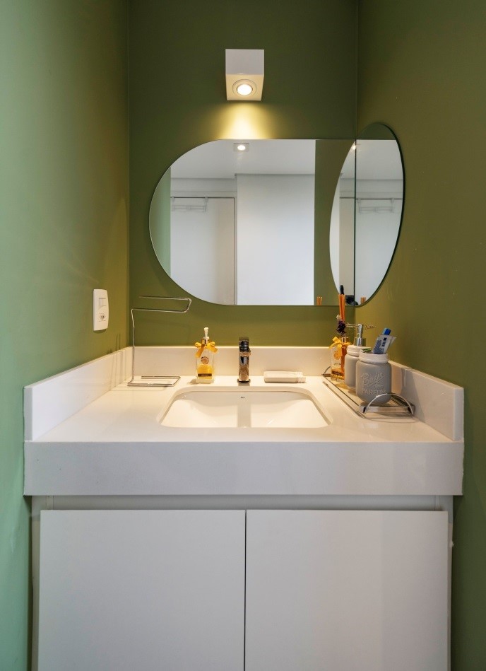 Banheiro com paredes verdes e espelho com desenho diferenciado, mas com a aposta nas curvas se destaca no projeto da arquiteta Tatiane Waileman | Foto: Emerson Rodrigues