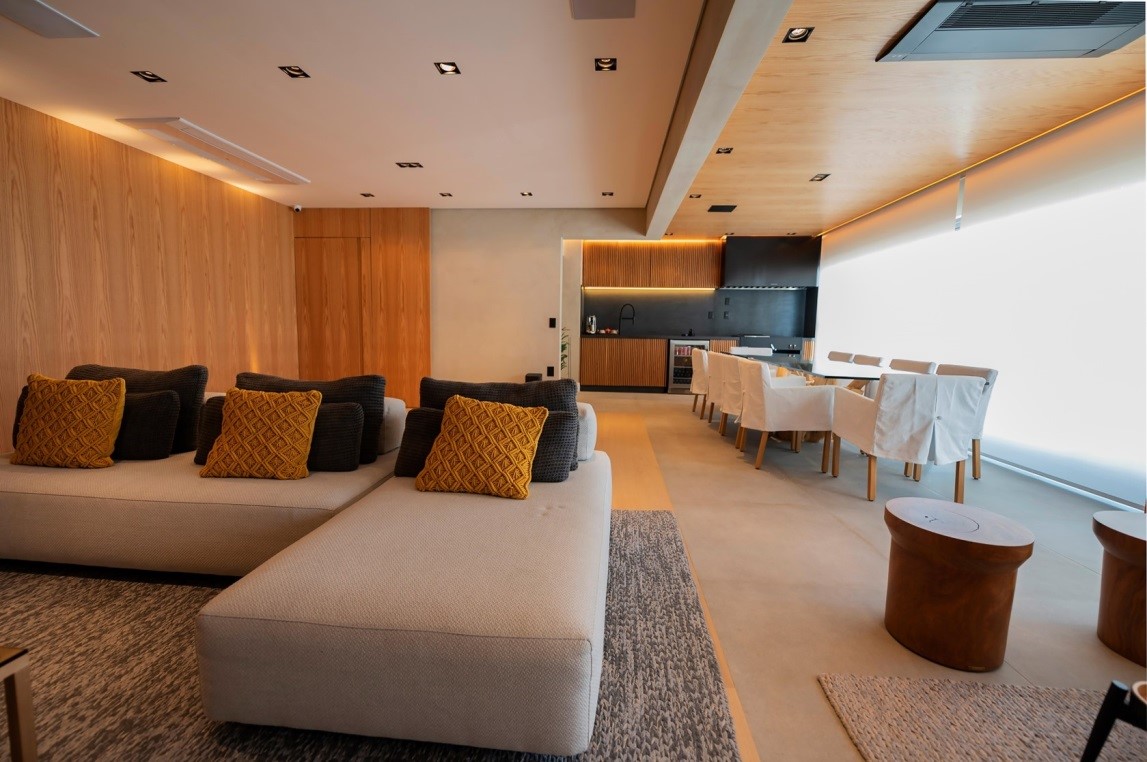 Sala de estar e área gourmet integradas: tons de bege, cinza e muita madeira trazem harmonia ao projeto do escritório Fan Interior Design | Foto: Emerson Rodrigues